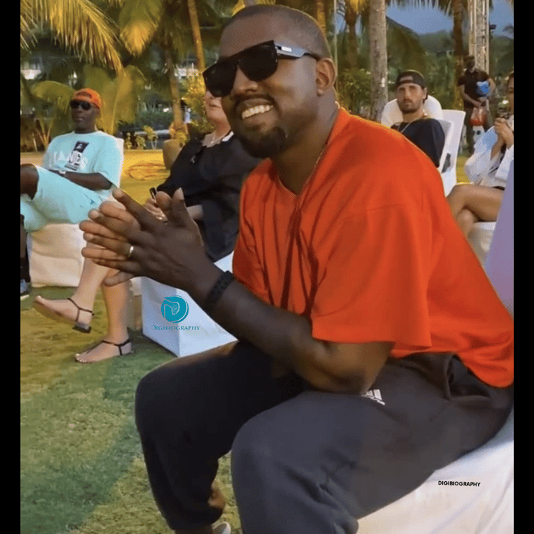 Kanye West sitting on the chair and wearing an orange t-shirt