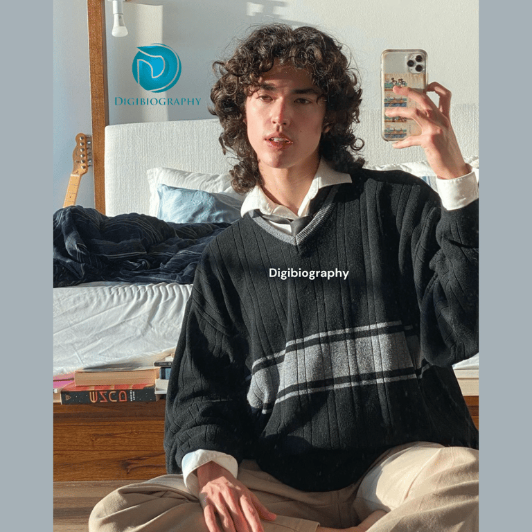 Conan Gray clicking a mirror photo in their room wearing a sweater