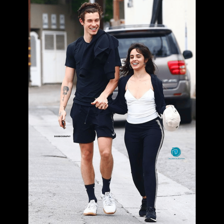 Camila Cabello stands with Shawn Mendes  and wearing a black-white dress