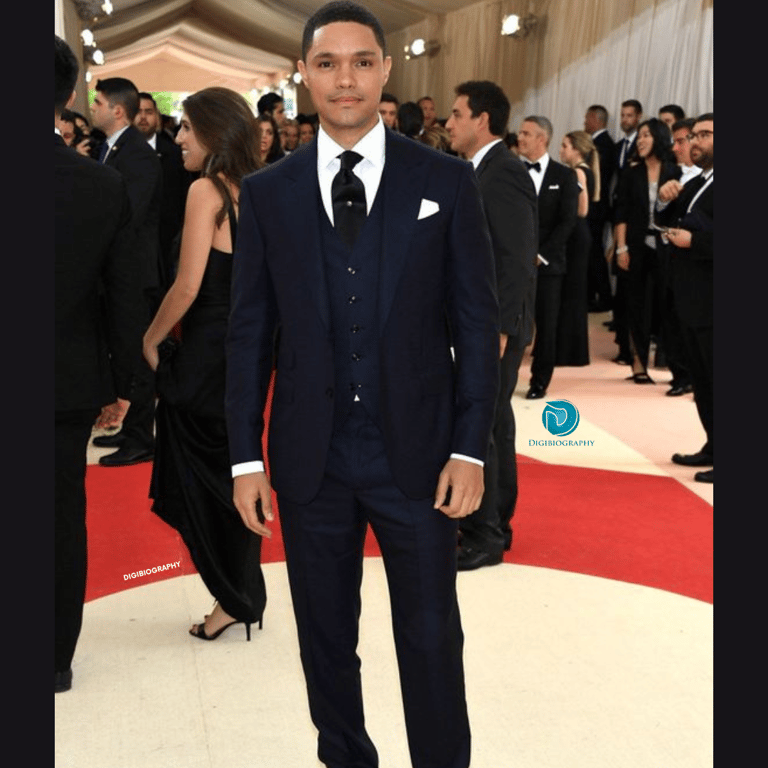 Trevor Noah attends a party and wears a black coat 