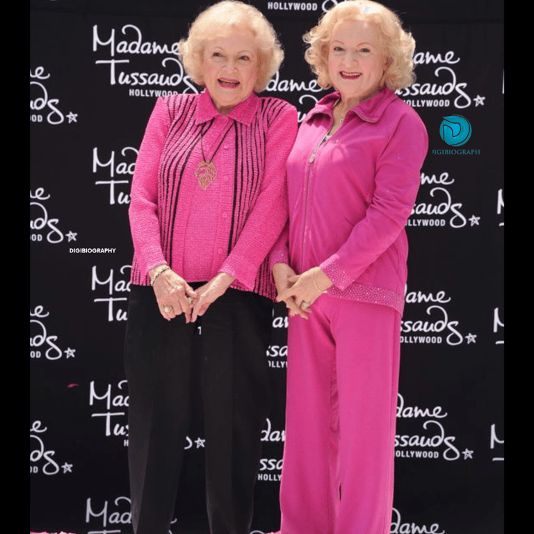 Betty White stands with her sister while wearing a pink and black dress
