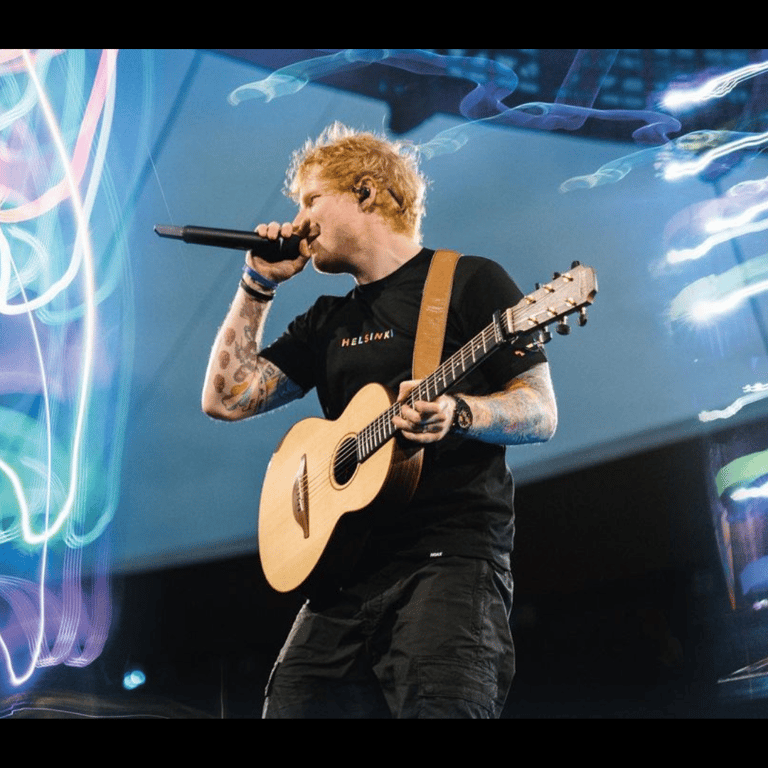 ED Sheeran wearing a black t-shirt while stand on the stage and sing a song