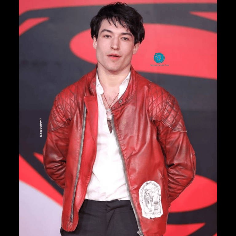 Ezra Miller stands on the stage and wearing a red jacket