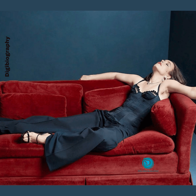 Rachel McAdams sitting on the sofa and wears a black dress