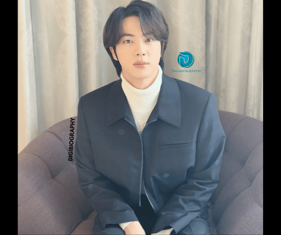 kim seok-jin wearing a black coat and sitting on the sofa