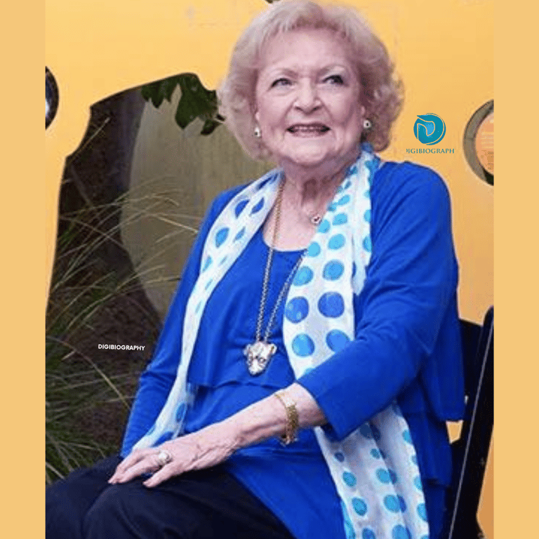 Betty White wearing a blue dress and sitting on the chair