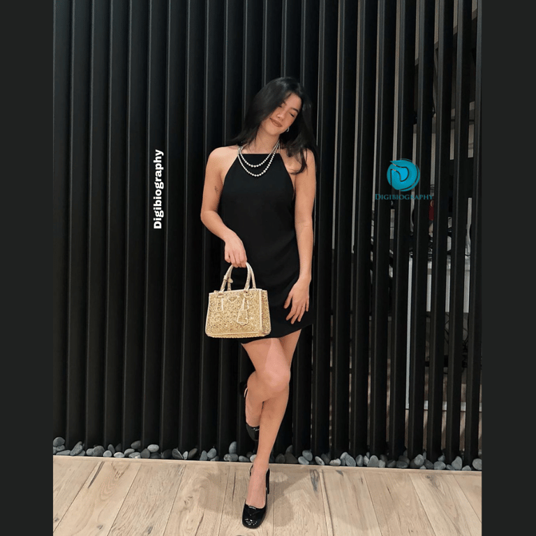Charli D'amelio wears a black dress and holding a golden bag in his hand
