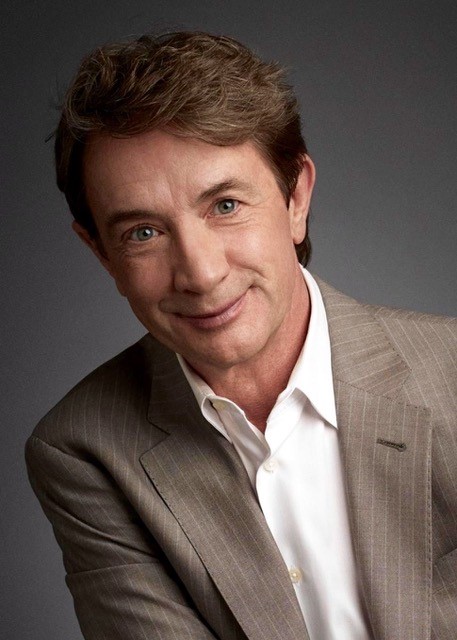 Martin Short wears a brown suit and gives a smile