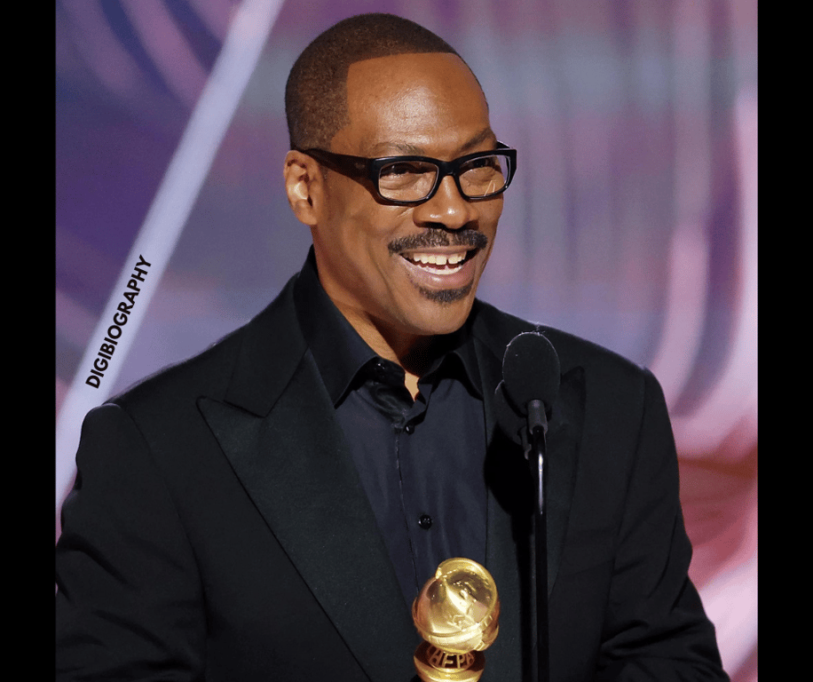 Eddie Murphy wearing a coat and takes an award