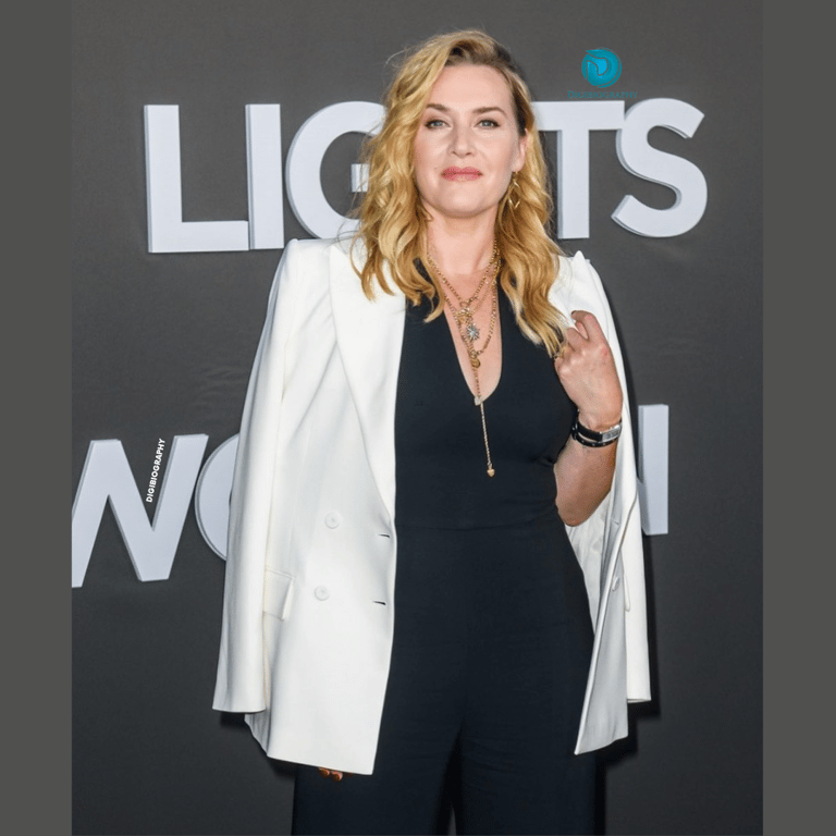 Kate Winslet wearing a white blazer and black dress while giving a look