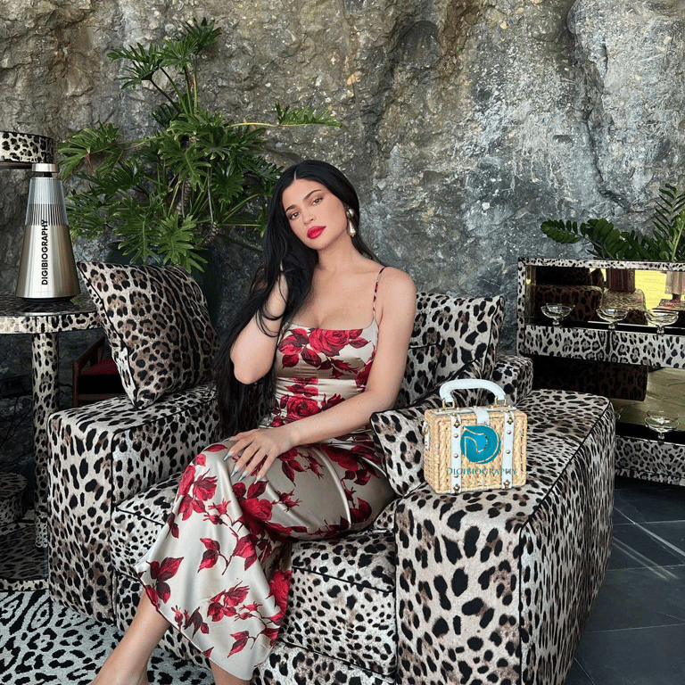 Kylie Jenner sitting on the sofa while wearing a silver-flower dress