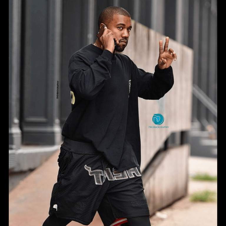 Kanye West wearing a black full slive t-shirt and gives a victory sign to her fans