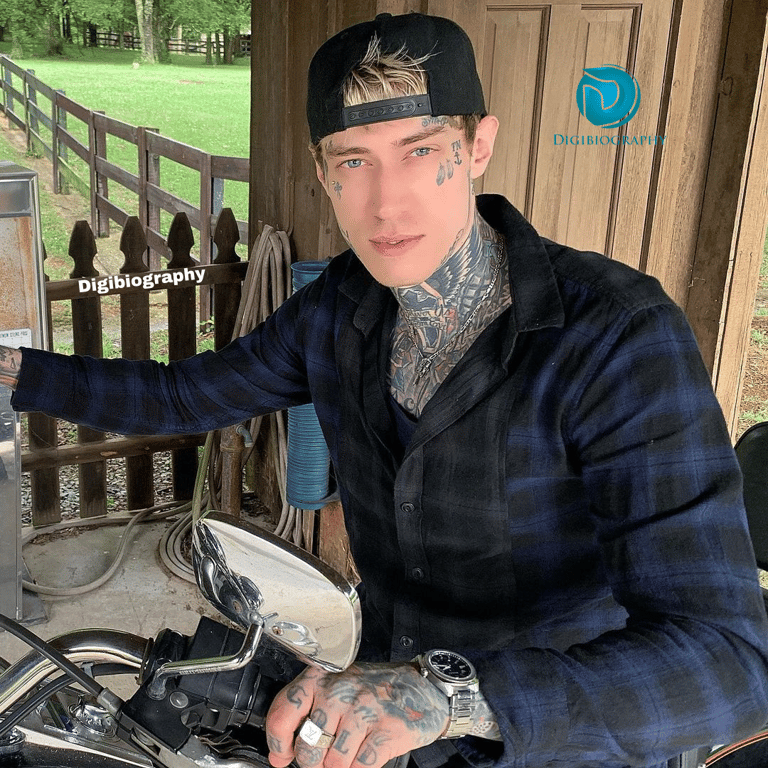 Trace Cyrus wears a blue checked shirt and sitting on the bike