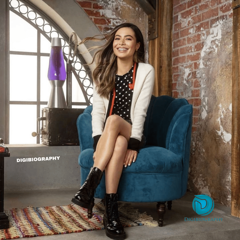 Miranda Cosgrove sitting on the sofa and wears a white and black dress