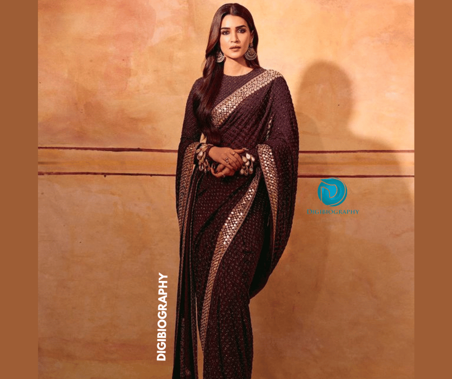 Kriti wearing a black saree and stand close to the wall