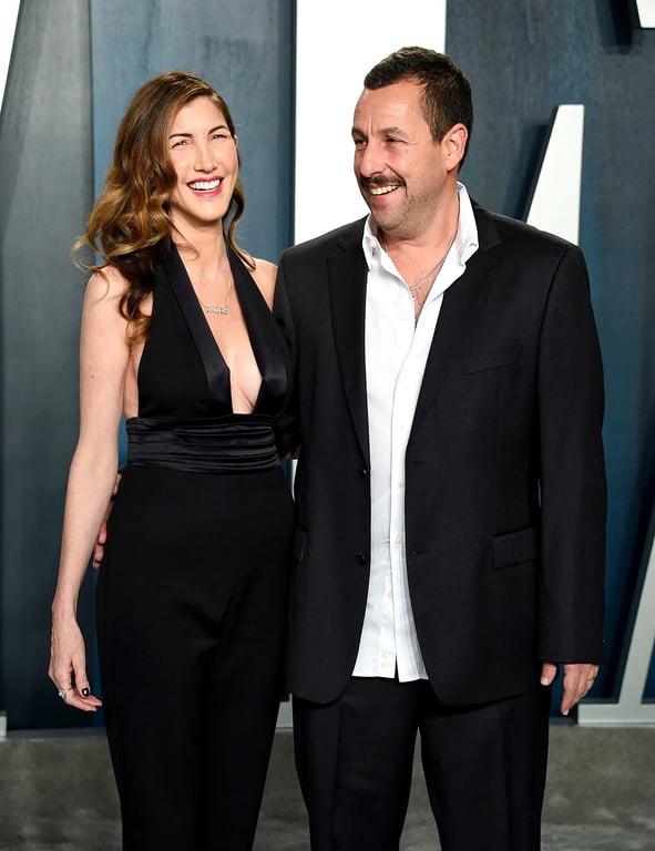 Adam Sandler stands with the wife while both are in same combination black dress