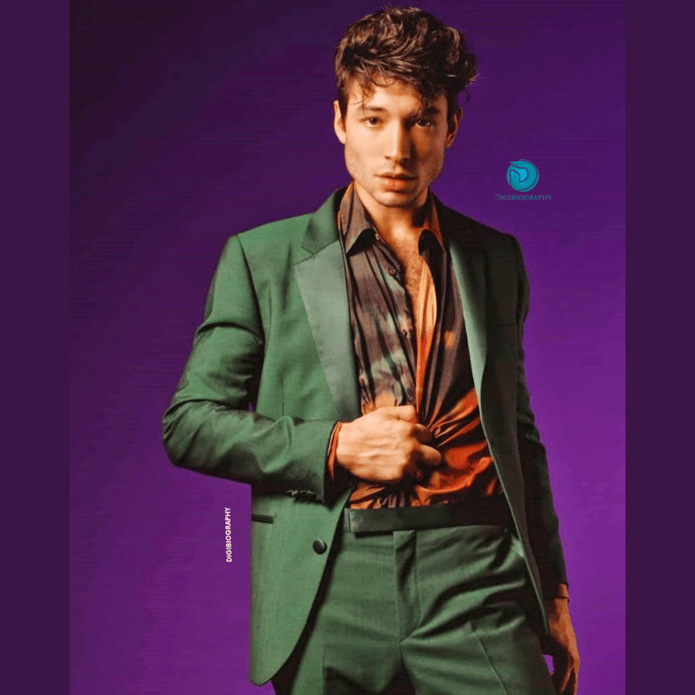 Ezra Miller wearing a green blazer stands in a purple background