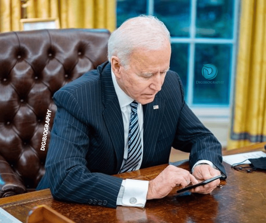 Joe Biden sitting on the chair while using her phone
