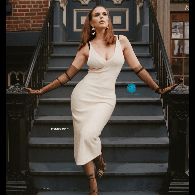 Julia Fox wearing a white dress while standing on the stairs