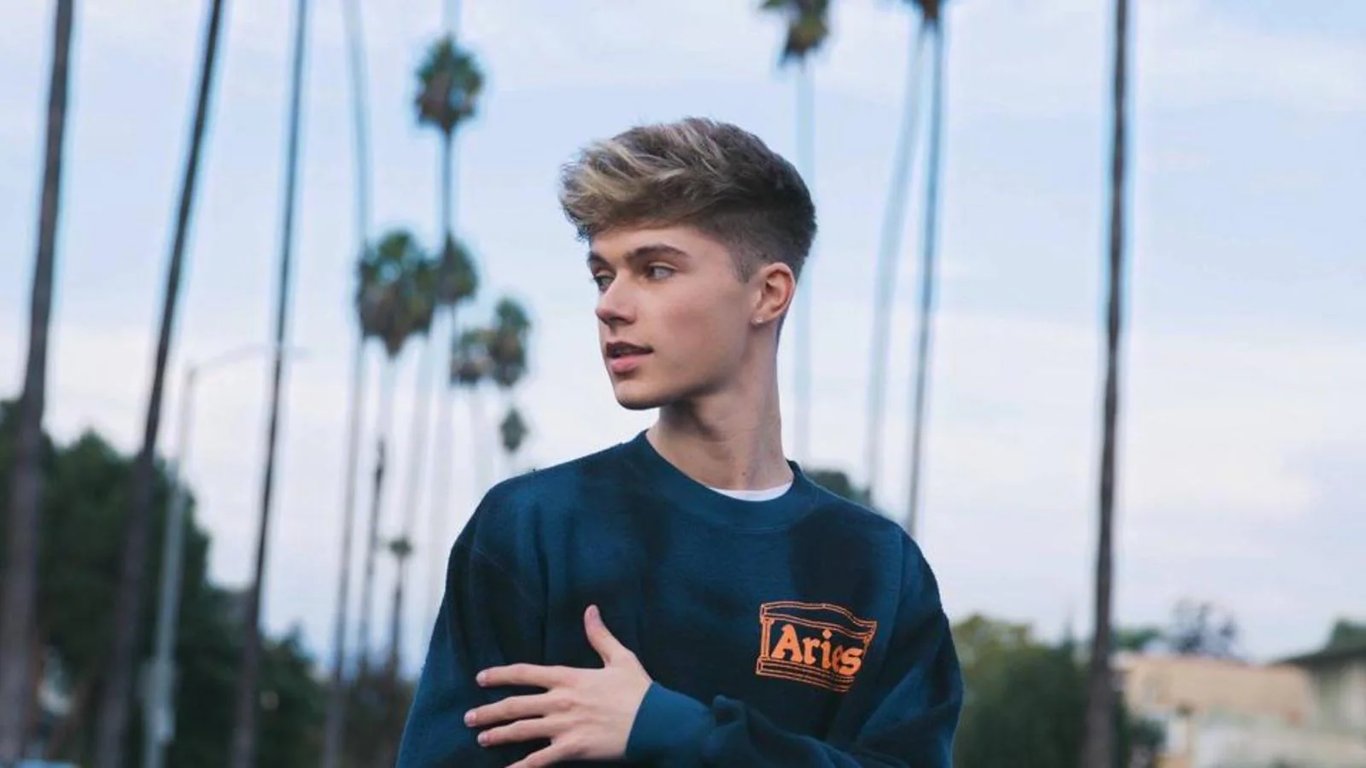 HRVY wearing a blue t-shirt and standing in the open area and gives a side look