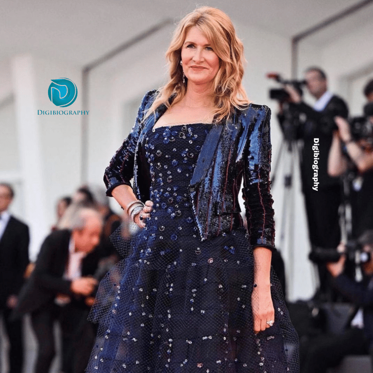 Laura Dern attends a function in a blue dress and stands in from of the media