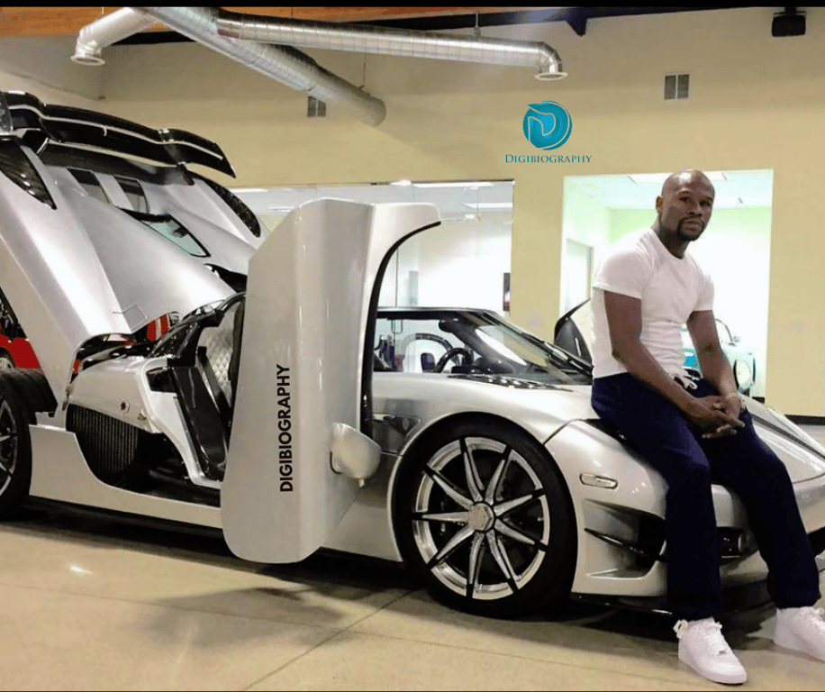 Floyd Mayweather sitting on the car bonnet and wears a white t-shirt