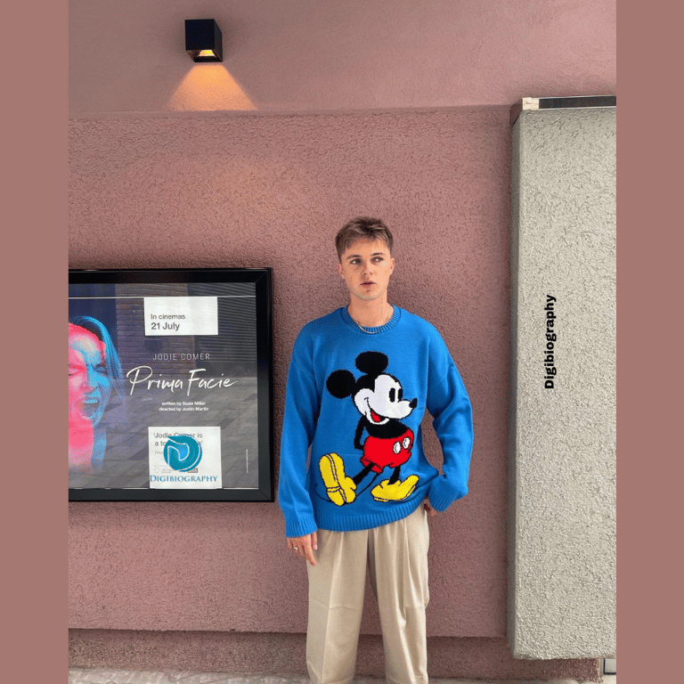 HRVY wearing a blue t-shirt and stand near by the wall