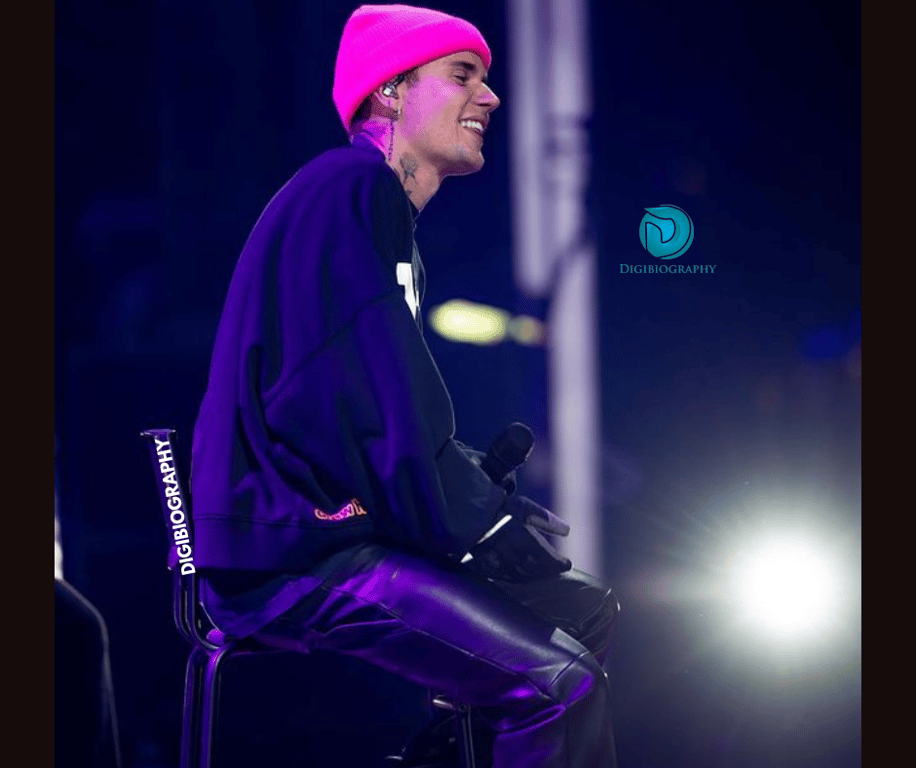 Justin Bieber sitting on the stage and gives a smile