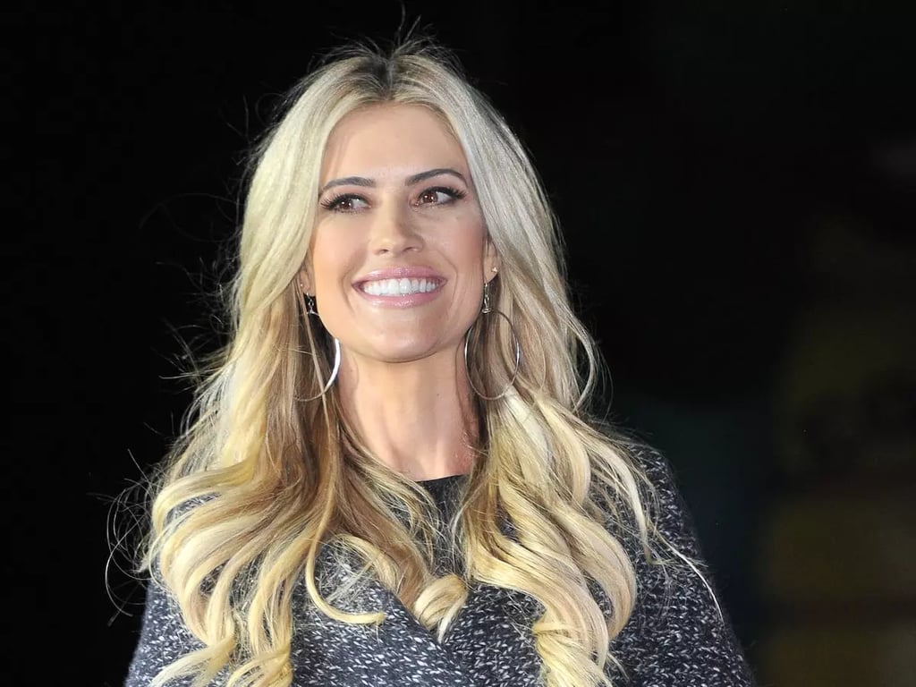 Christina Anstead gives a smile and stands in a dark shadow