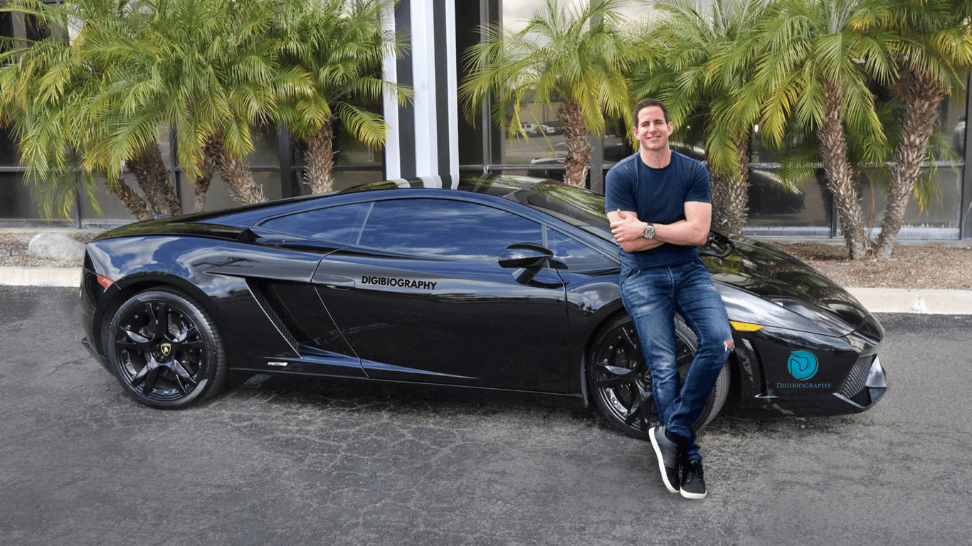 Tarek El Moussa stands next to her car while wearing a blue T-shirt