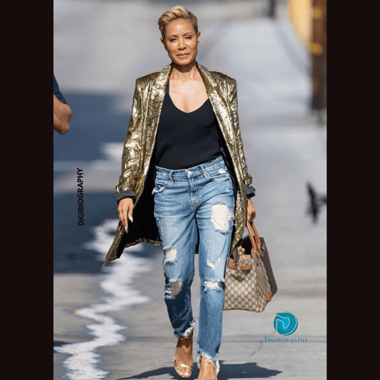 Jada Pinkett Smith walking on the road while wearing a golden jacket with a black t-shirt and jeans
