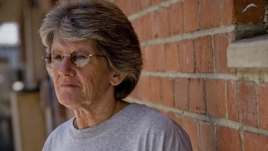 Leslie Van Houten Standing Side of Wall wearing a Glass