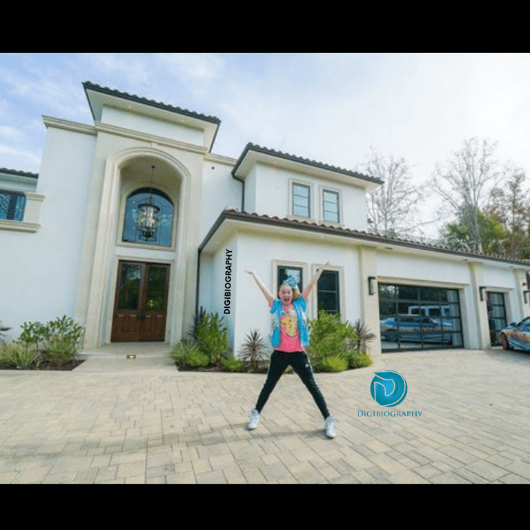 Jojo Siwa stands next to her house