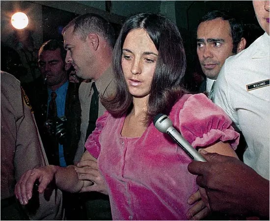 Susan Atkins holding by the Police and wearing a pink top