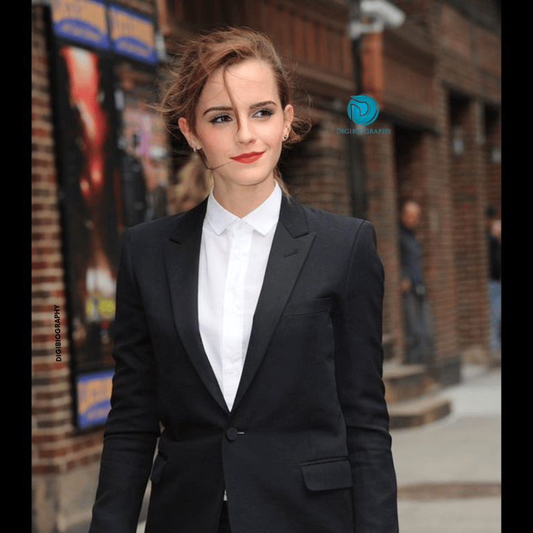 Emma Watson wearing a black coat with a white shirt and gives a look