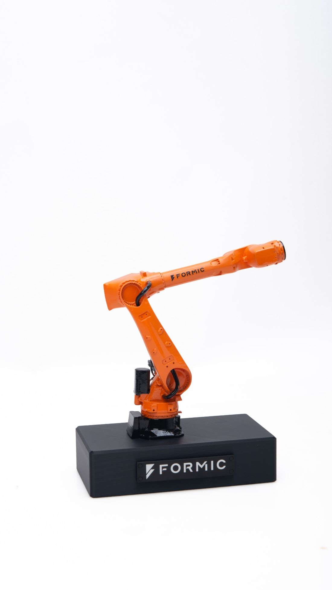 An orange scale model of a Formic robot arm on a black base with the Formic logo