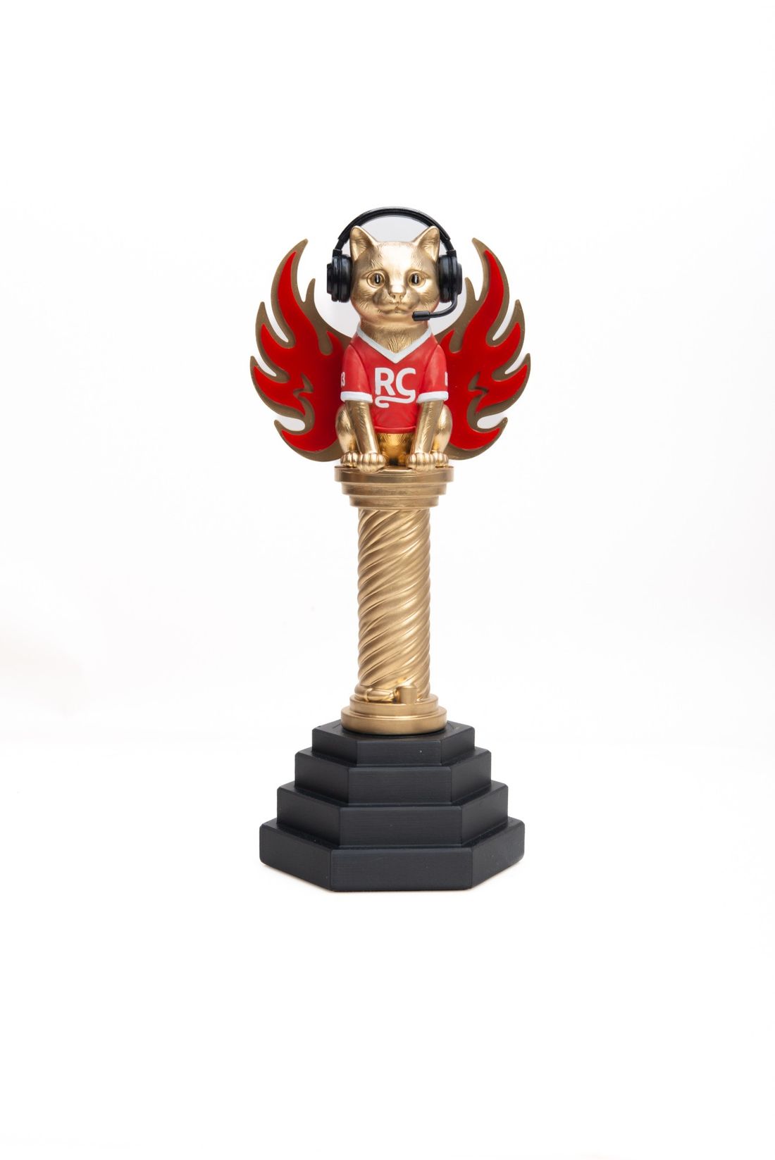 A gold cat trophy in a red RC jersey and headset with flame wings, on a twisted gold column and black stepped base