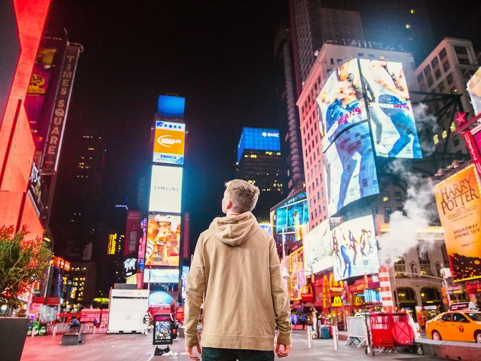 Kid in middle of a city at night looking at the city lights above him