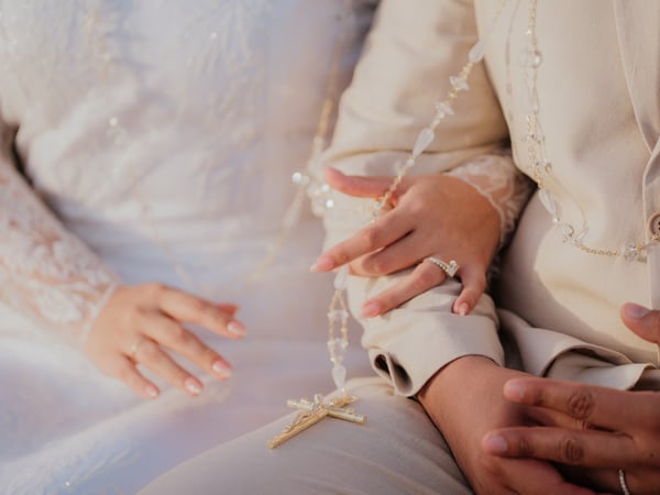Detalle de ceremonia religiosa con lazo de perlas y crucifijo durante boda en playa