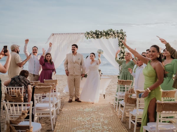 Ceremonia de boda en playa con arco floral blanco y sillas frente al océano Pacífico