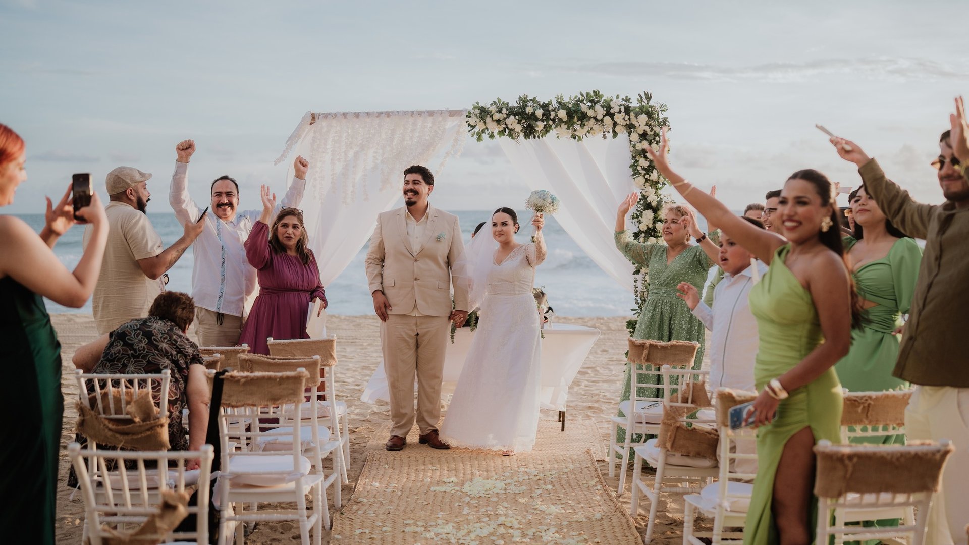 Ceremonia de boda en playa con arco floral blanco y sillas frente al océano Pacífico