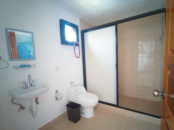 Baño completo con lavabo de pedestal, inodoro y regadera con puerta de vidrio esmerilado