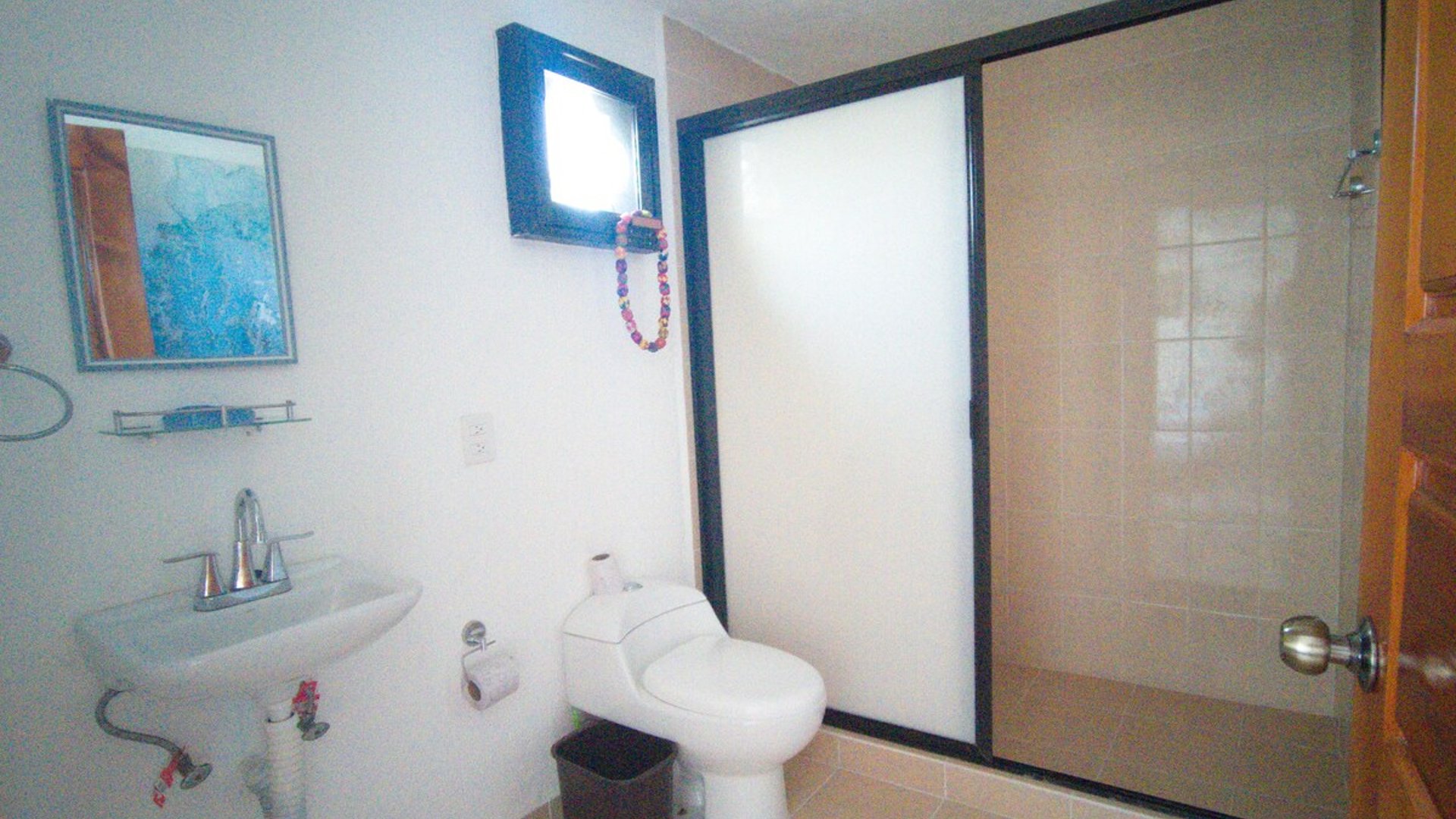 Baño completo con lavabo de pedestal, inodoro y regadera con puerta de vidrio esmerilado