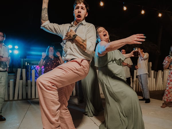 Invitados bailando en pista nocturna de boda con luces colgantes y ambiente festivo tropical