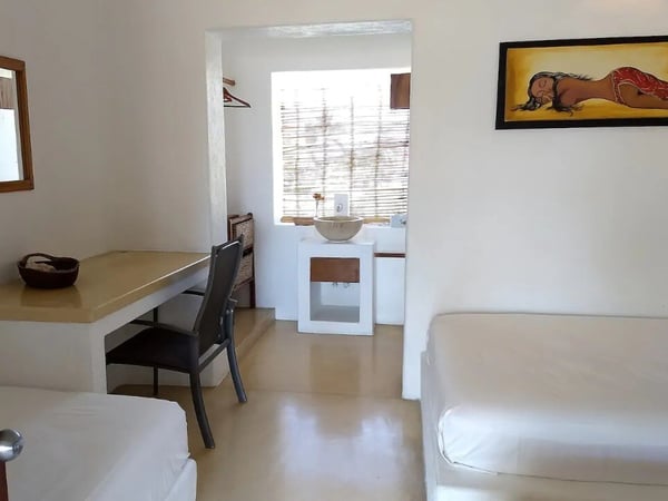 Habitación doble con paredes blancas, escritorio de concreto, lavabo integrado y cuadro decorativo en estilo rústico-contemporáneo
