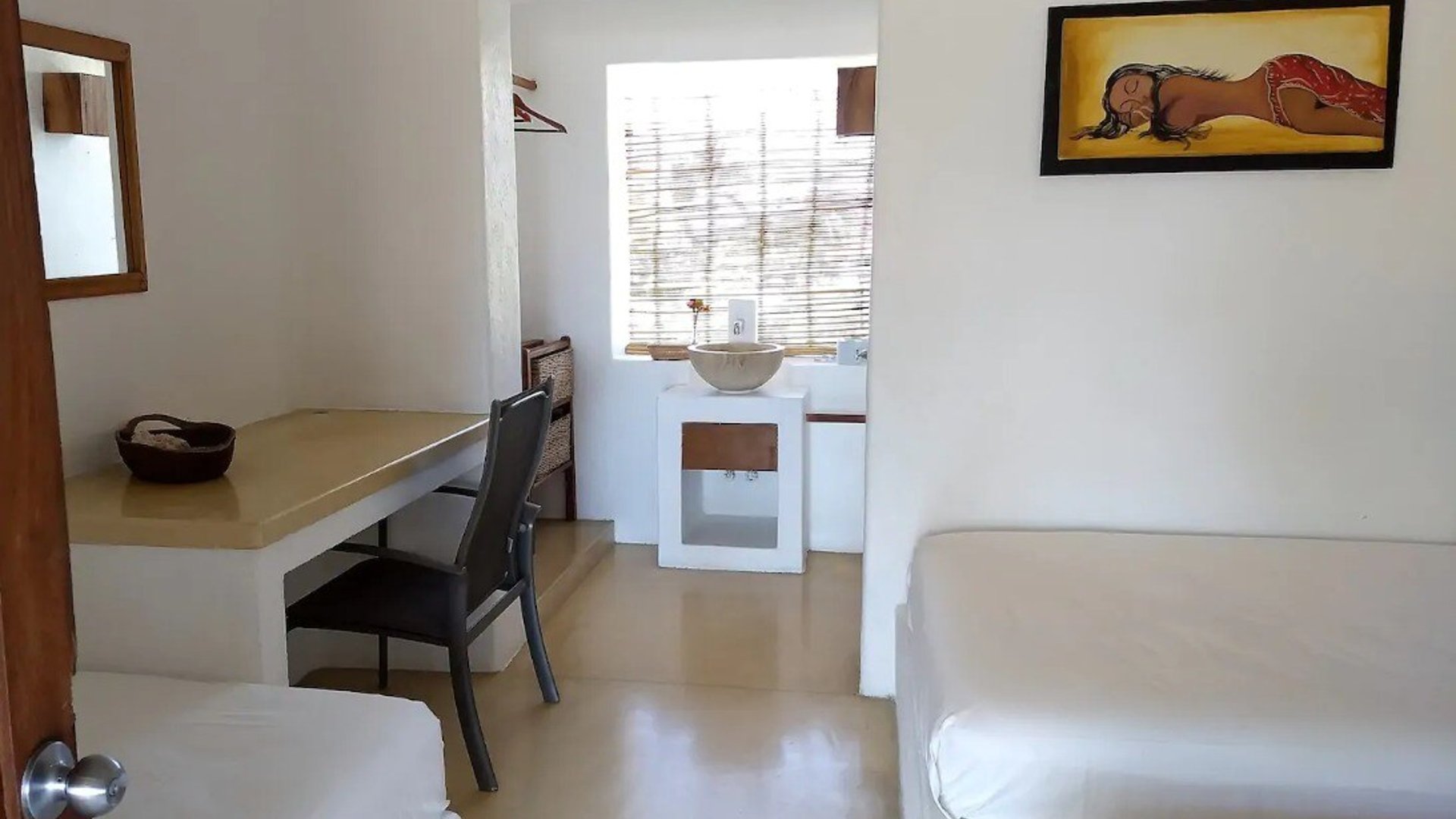 Habitación doble con paredes blancas, escritorio de concreto, lavabo integrado y cuadro decorativo en estilo rústico-contemporáneo