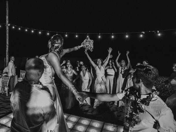 Lanzamiento de ramo en recepción nocturna con luces colgantes e invitadas en pista de baile