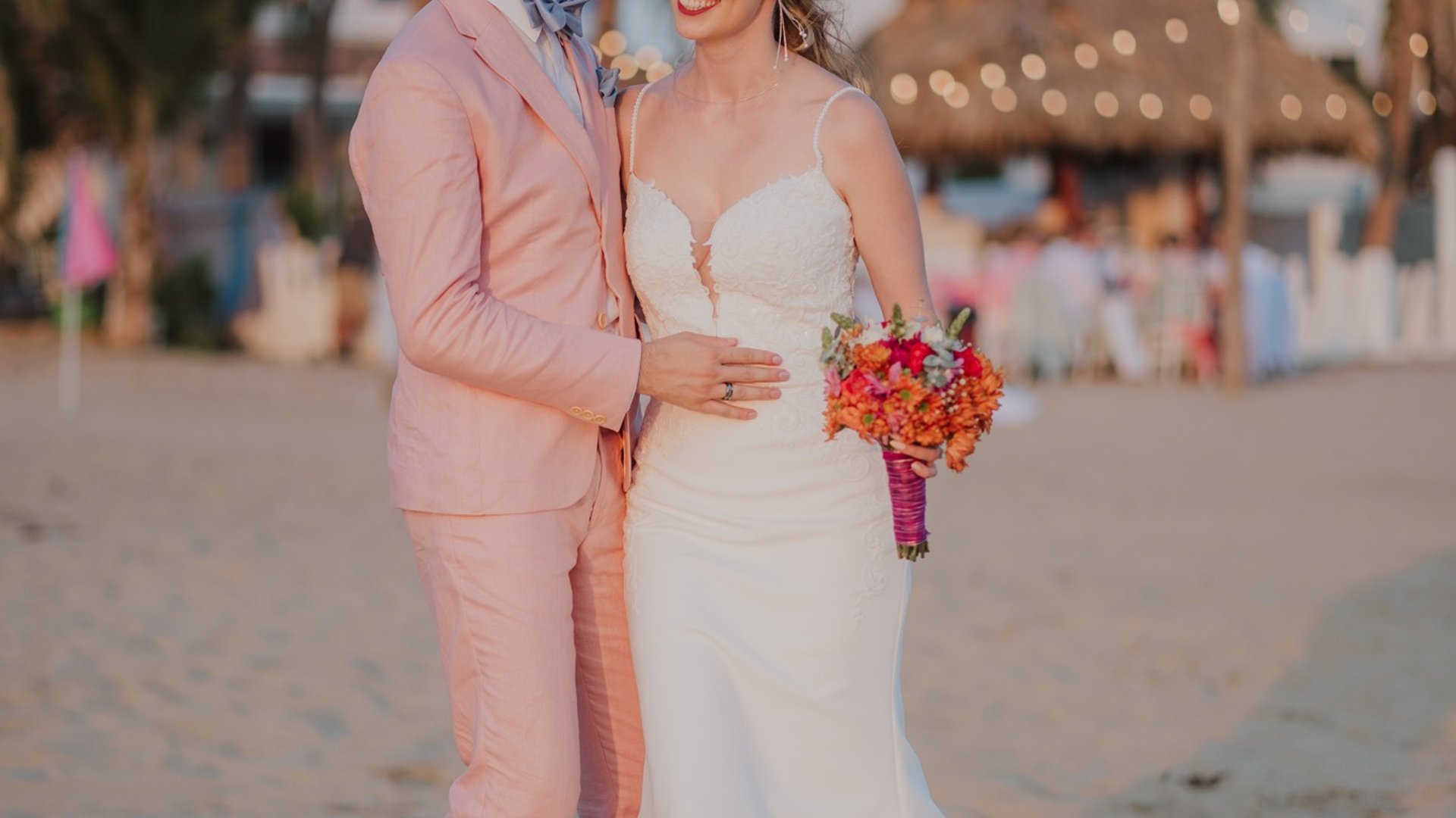 Boda en playa frente a villa con palmeras y palapa iluminada al atardecer en Pie de la Cuesta