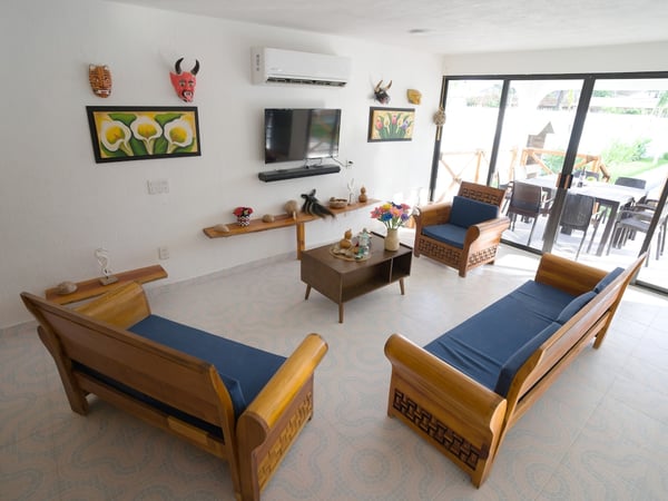 Sala amplia con muebles de madera y cojines azules, decoración artesanal en paredes y acceso a terraza exterior