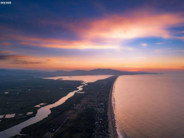 Vista aérea al atardecer de la franja costera de Pie de la Cuesta con laguna, playa y cielo en tonos naranja y violeta